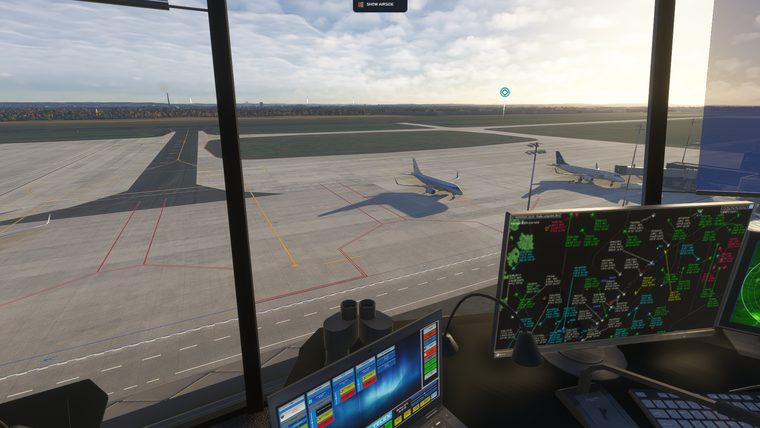 Inside the tower cab at Rzeszów, radar screens on the desk and two airliners on the apron outside.