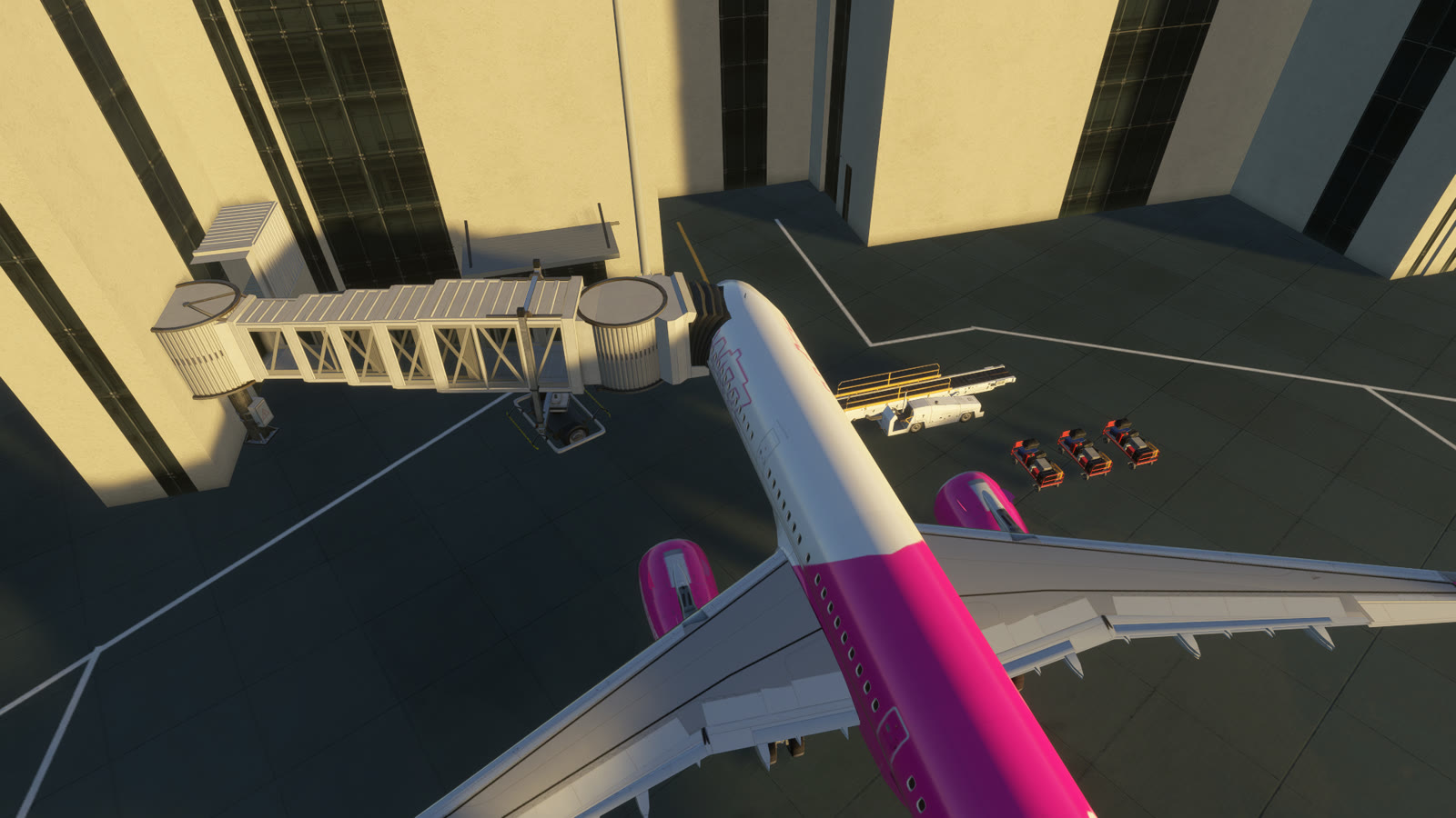 From above, a jet bridge docked at the front door of a Wizz Air A321neo at Frankfurt, with a belt loader and baggage carts on the other side